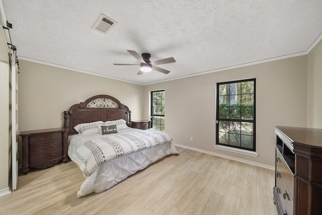 bedroom with ceiling fan, a textured ceiling, light wood-type flooring, and multiple windows