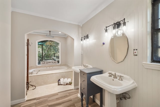 bathroom featuring crown molding, hardwood / wood-style floors, sink, and a relaxing tiled tub