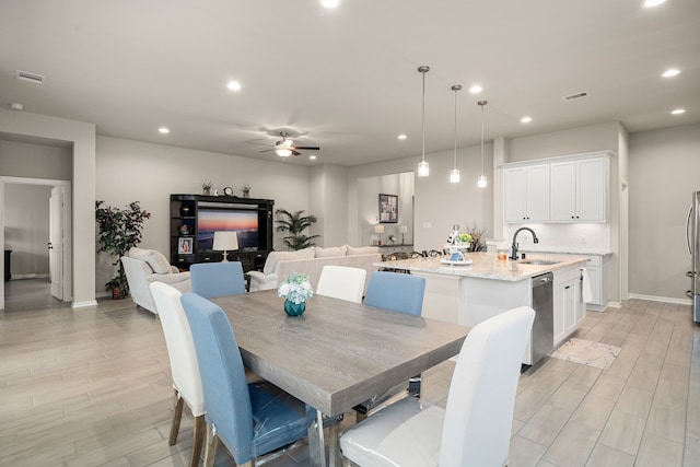 dining room featuring ceiling fan, sink, and light hardwood / wood-style floors