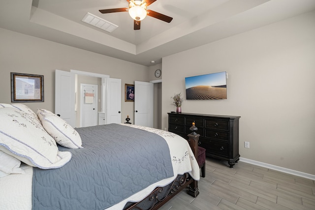 bedroom featuring a tray ceiling, ceiling fan, and light hardwood / wood-style flooring