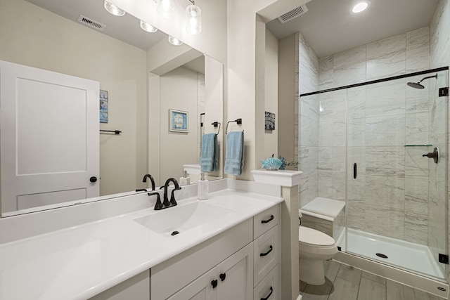 bathroom with vanity, toilet, and a shower with door