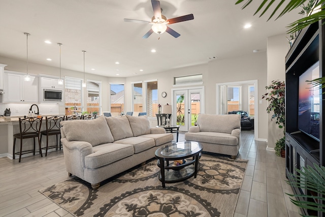 living room featuring french doors, light wood-type flooring, and ceiling fan