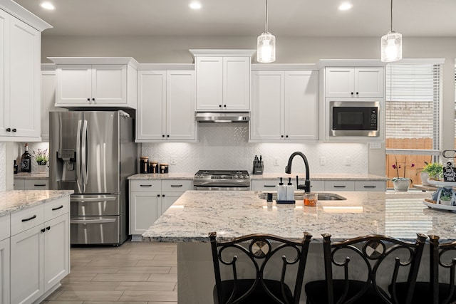 kitchen featuring stainless steel appliances, a kitchen bar, decorative light fixtures, and sink