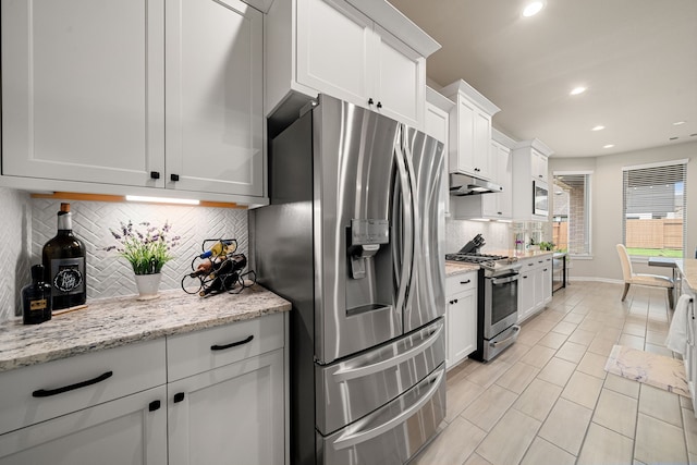 kitchen with appliances with stainless steel finishes, backsplash, light stone counters, and white cabinets