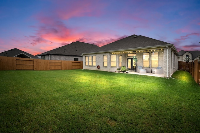 back house at dusk with a yard and a patio area