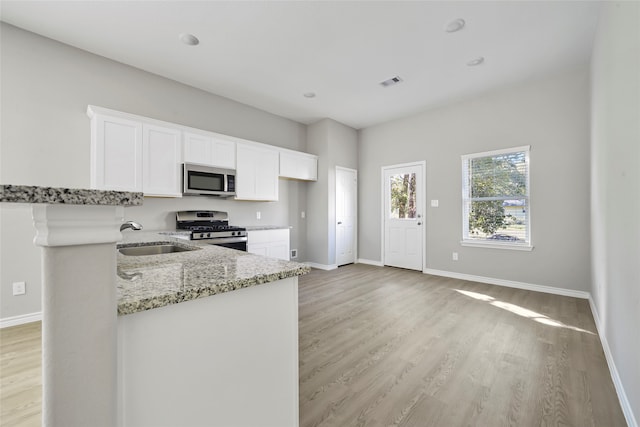 kitchen featuring sink, light hardwood / wood-style flooring, white cabinetry, appliances with stainless steel finishes, and light stone countertops