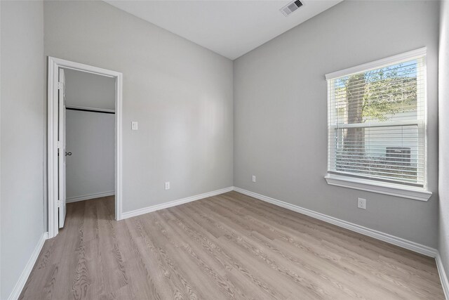 unfurnished bedroom featuring light hardwood / wood-style floors, a spacious closet, and a closet