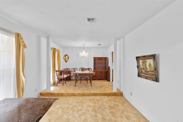 carpeted dining room with a textured ceiling and an inviting chandelier