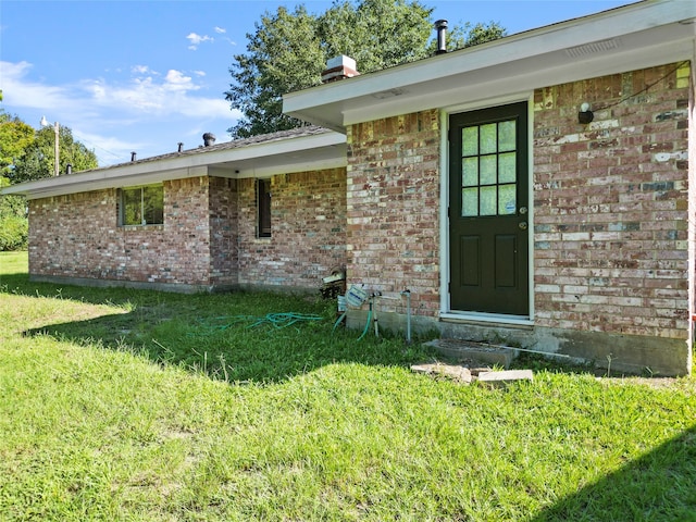 view of exterior entry with a lawn