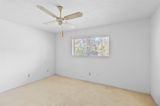 empty room featuring ceiling fan, light colored carpet, and a textured ceiling