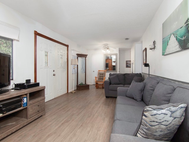 living room with a textured ceiling, light hardwood / wood-style floors, and ceiling fan