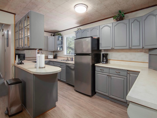 kitchen with stainless steel appliances, light wood-type flooring, sink, and gray cabinetry