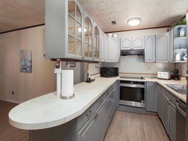 kitchen featuring light wood-type flooring, black appliances, gray cabinetry, and sink