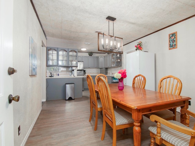 dining area featuring a notable chandelier, light hardwood / wood-style floors, and ornamental molding