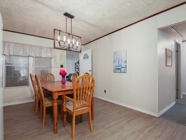 dining area featuring wood-type flooring, ornamental molding, and a chandelier