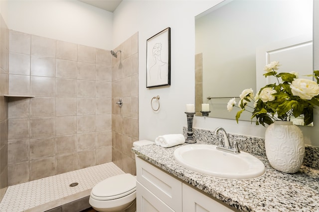 bathroom with tiled shower, vanity, and toilet