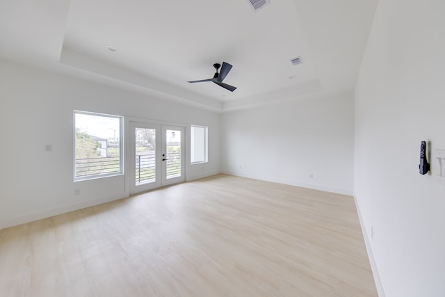 unfurnished room with a tray ceiling, ceiling fan, and light hardwood / wood-style flooring