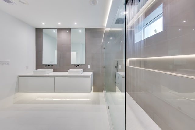 bathroom with a tile shower, vanity, and tile patterned floors