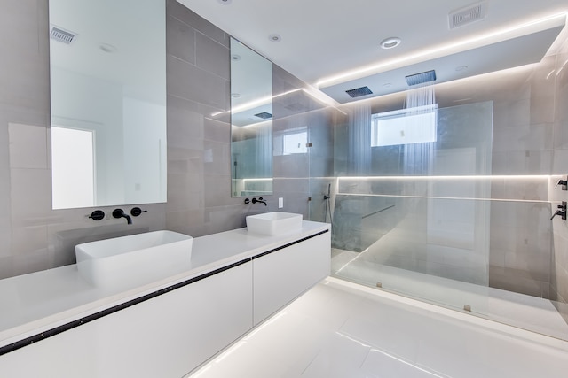 bathroom with vanity, tile walls, a tile shower, and tile patterned floors