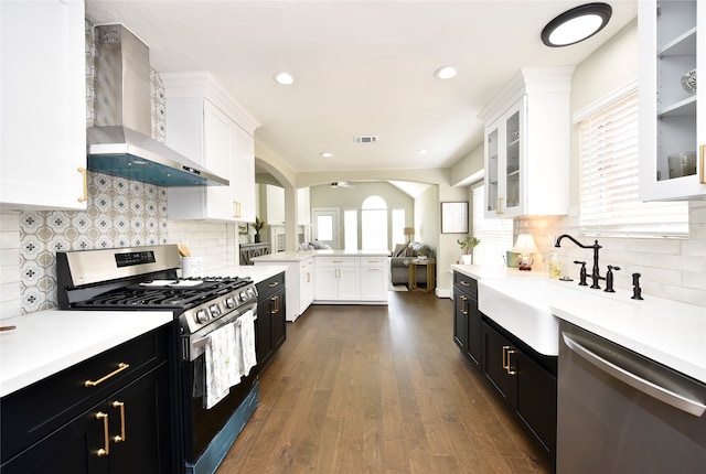 kitchen featuring white cabinets, wall chimney exhaust hood, stainless steel appliances, decorative backsplash, and dark hardwood / wood-style flooring