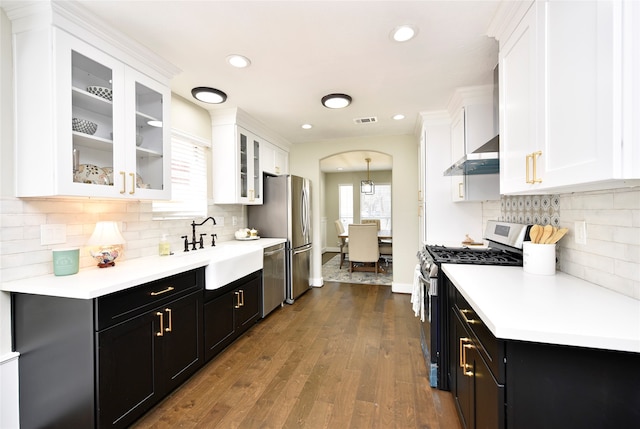 kitchen featuring decorative backsplash, white cabinets, pendant lighting, stainless steel appliances, and hardwood / wood-style floors