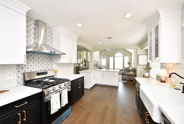 kitchen featuring wall chimney exhaust hood, gas stove, dark hardwood / wood-style floors, and tasteful backsplash