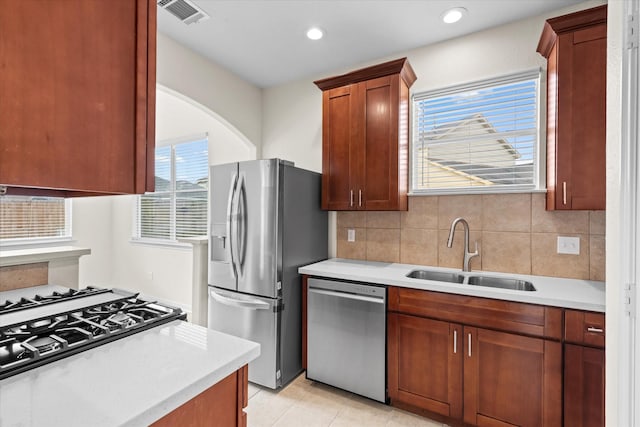 kitchen with tasteful backsplash, sink, light tile patterned floors, and stainless steel appliances