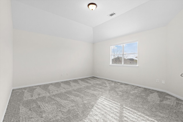 carpeted spare room with vaulted ceiling