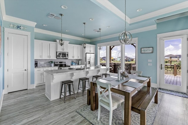 dining space featuring an inviting chandelier, crown molding, and light hardwood / wood-style floors