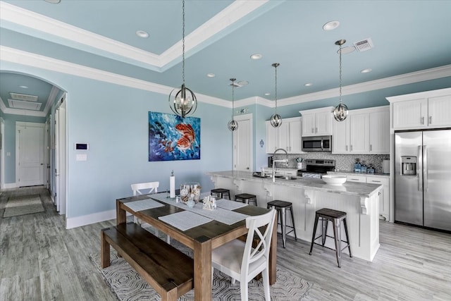 dining area with sink, light wood-type flooring, and ornamental molding