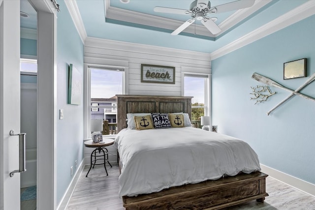 bedroom with multiple windows, a raised ceiling, light wood-type flooring, and ceiling fan