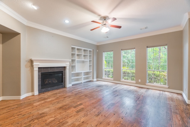 unfurnished living room with ceiling fan, a tile fireplace, hardwood / wood-style flooring, and crown molding