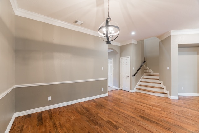 empty room with a notable chandelier, crown molding, and hardwood / wood-style flooring