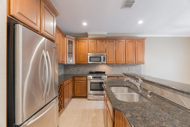 kitchen with light tile patterned floors, sink, tasteful backsplash, appliances with stainless steel finishes, and dark stone counters