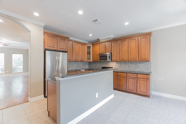 kitchen featuring ornamental molding, stainless steel appliances, a center island, and light tile patterned floors