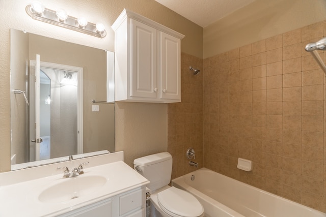 full bathroom with a textured ceiling, tiled shower / bath combo, vanity, and toilet