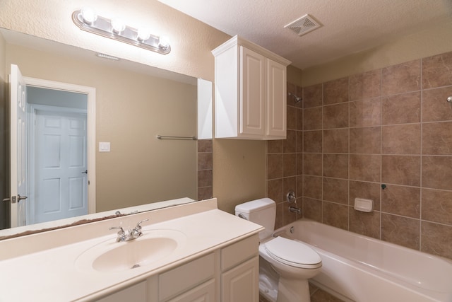 full bathroom featuring vanity, a textured ceiling, tiled shower / bath combo, and toilet