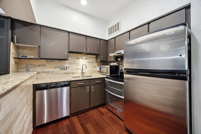 kitchen with decorative backsplash, dark hardwood / wood-style floors, stainless steel appliances, sink, and light stone counters