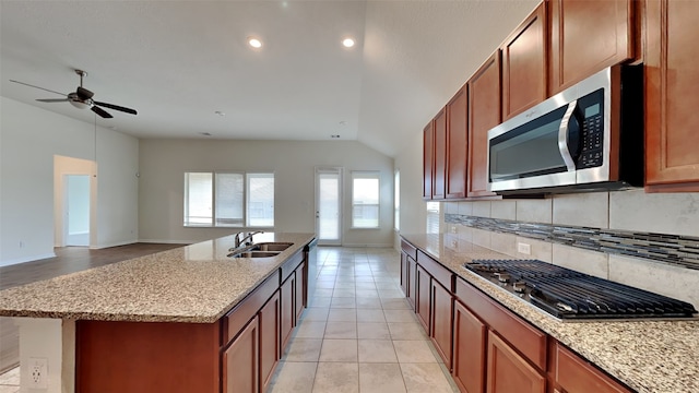 kitchen featuring sink, an island with sink, lofted ceiling, stainless steel appliances, and backsplash