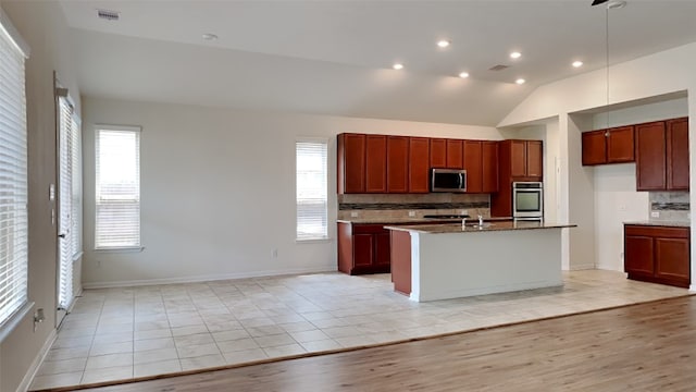 kitchen featuring stainless steel appliances, plenty of natural light, vaulted ceiling, and light hardwood / wood-style flooring