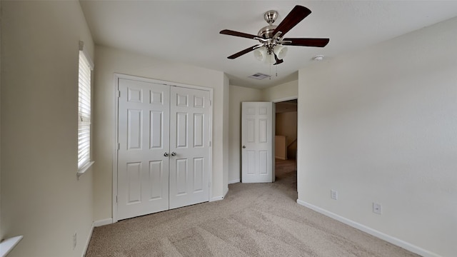 unfurnished bedroom with ceiling fan, light colored carpet, a closet, and multiple windows