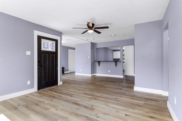 unfurnished living room featuring a textured ceiling, ceiling fan, and light hardwood / wood-style floors