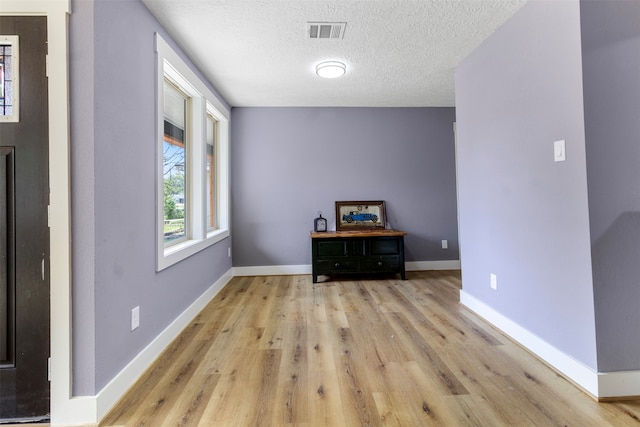 empty room with a textured ceiling and light wood-type flooring