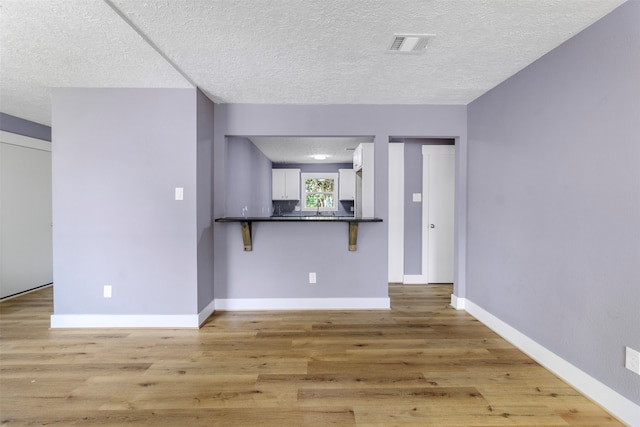 unfurnished living room with a textured ceiling and light wood-type flooring