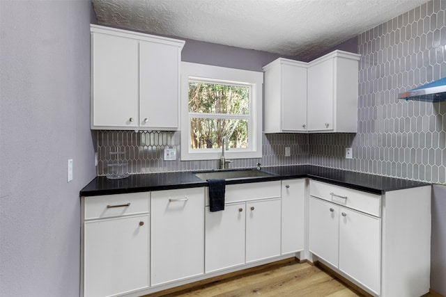 kitchen featuring white cabinets, sink, backsplash, and a textured ceiling