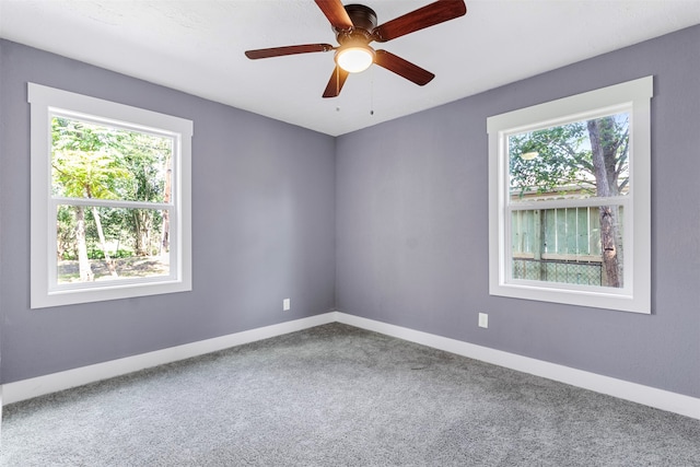 carpeted empty room featuring ceiling fan and a wealth of natural light