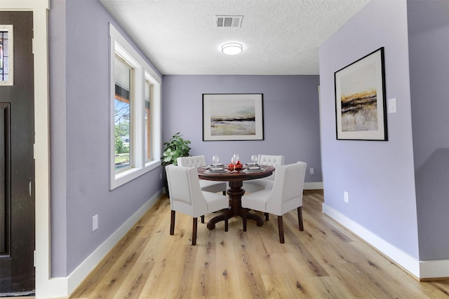 dining room with a textured ceiling and light wood-type flooring