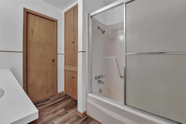 bathroom with wood-type flooring, shower / bath combination with glass door, and vanity