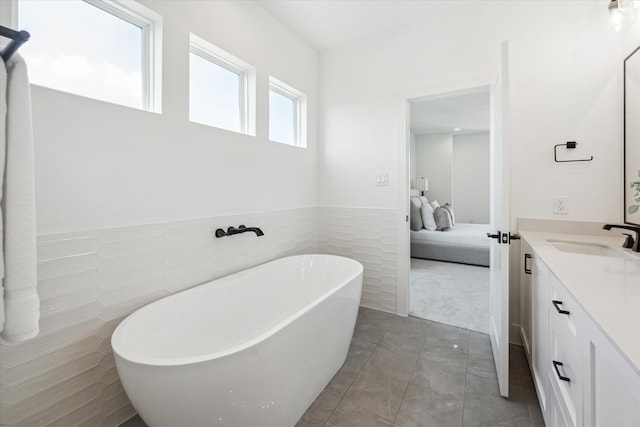 bathroom featuring tile walls, plenty of natural light, vanity, and a washtub