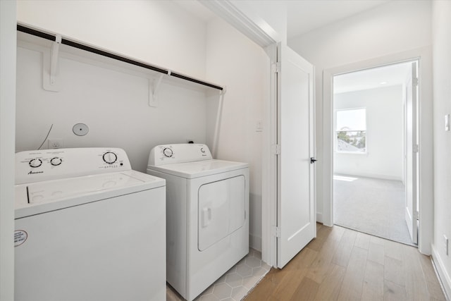 laundry room featuring washing machine and clothes dryer and light hardwood / wood-style flooring